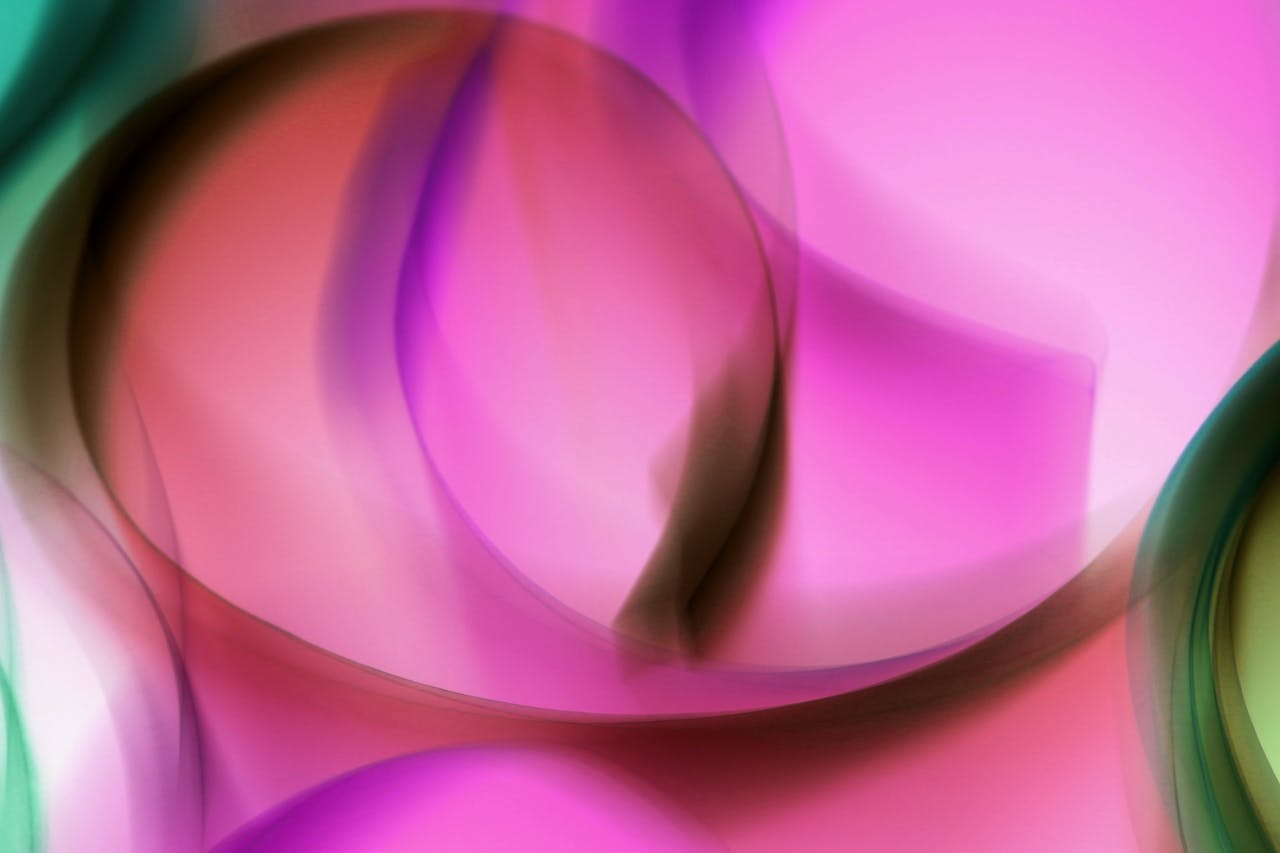 Vibrant abstract image featuring dynamic swirls of pink, purple, and green creating a fluid motion effect.